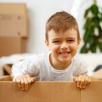Little boy playing inside a moving box on a moving day